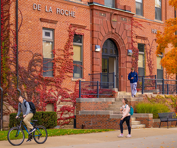 Students near De La Roche Hall entrance.