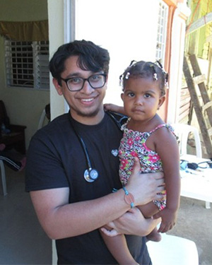 Students Without Borders member holds a toddler at a DR clinic.