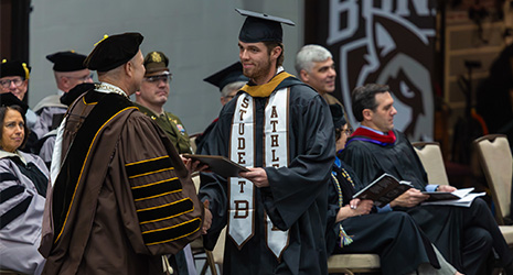 President hands graduate diploma.