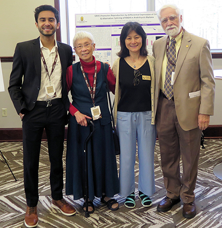 Iesh poses with the Wordens and Dr. Zhang, next to a poster about his research.