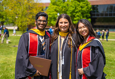 Three graduates sporting regalia.