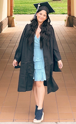 Priscilla poses in her graduation robe near Dev Hall 