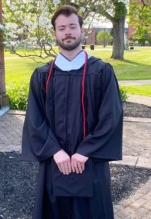 Tucker poses on the campus quad in his graduation gown