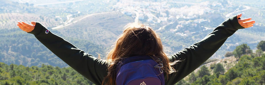 Student with arms outstretched overlooking a valley in Europe