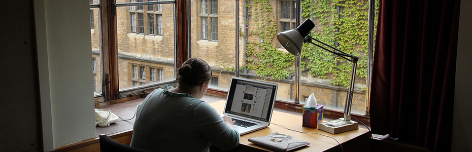 Student studying at a desk by a window overlooking the Trinity campus