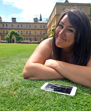 Smiling student lying on the lawn on campus