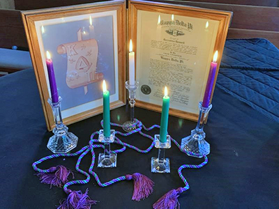 Burning candles in front of a framed honor society certificate