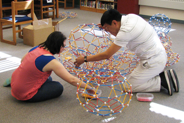 Mr. Cooke and Cassandra added white struts to the bottom to create a base to buttress the structure. Mr. Cooke and Cassandra build a base for the final structure.