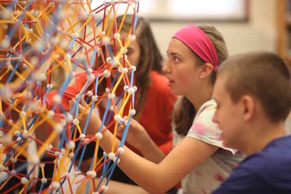 As the structure grew, many people could work on it at the same time. Several students work on the structure.