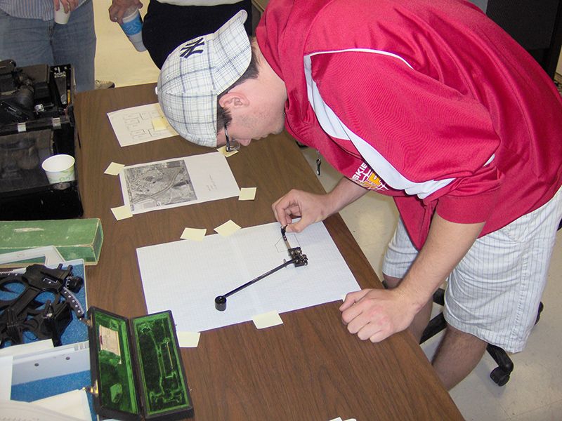 A student uses a polar planimeter to measure the area of a region by tracing its boundary. A student uses a polar planimeter to measure the area of a region by tracing its boundary.