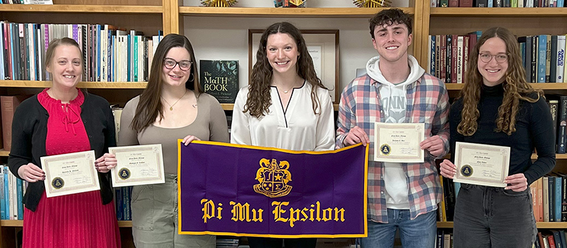 The five new inductees pose with the Pi Mu Epsilon banner.