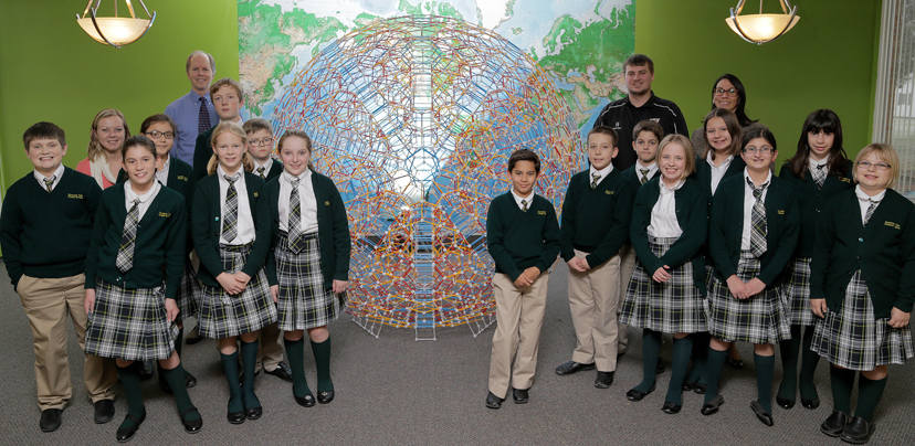 The group of 5th- and 6th-grade students, Dr. Hill, Jordan Farnham, and Michael Karl surround the Zometool cantitruncated hypericosahedron at Southern Tier Catholic School.