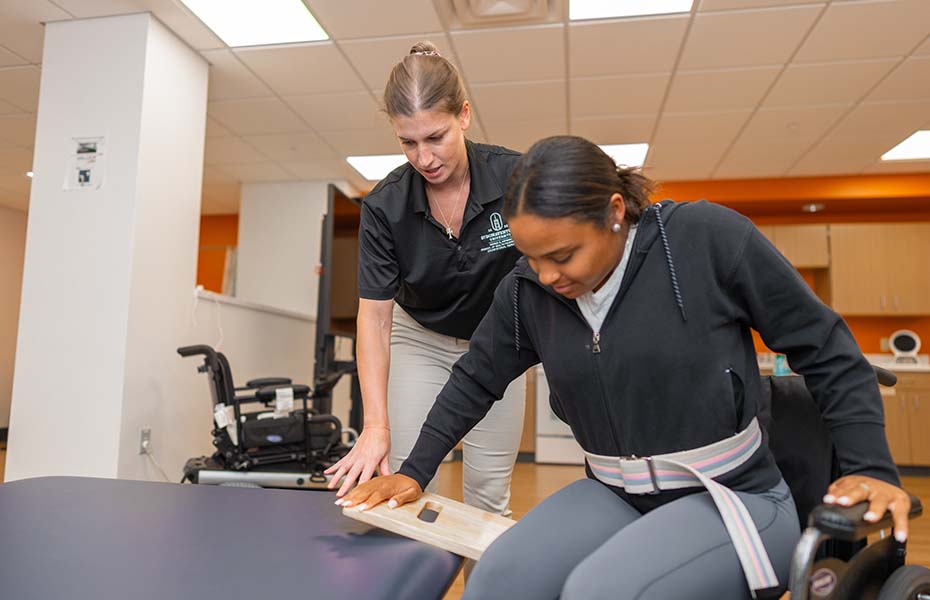 Using assistive equipment to move from wheelchair to bed.