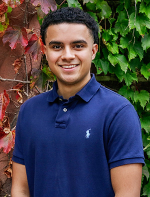 Alberto stands in front of red and green ivy