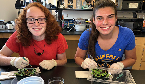High School Student Research Project Two smiling students doing plant research