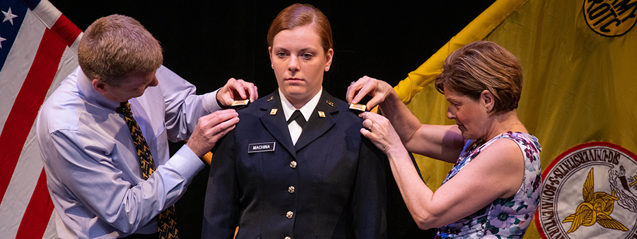 A female cadet with her parents at ROTC commissioning ceremony.