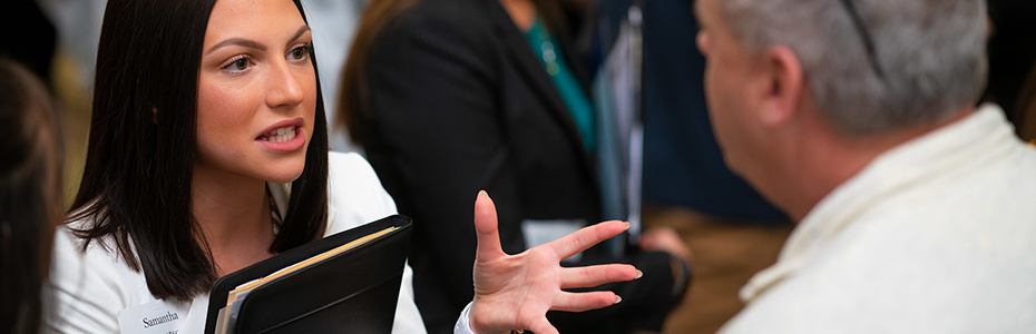 Student gesturing while talking at a presentation