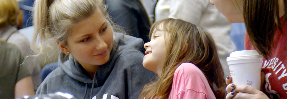Student with her smiling Bona buddy at a basketball game.