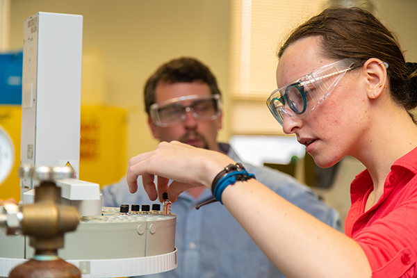Katie Heitzman works in the chemistry lab as Dr. Scott Simpson looks on.