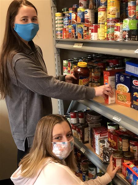 Grace Seeley and Olivia Lattimer stock the Bona Food Pantry