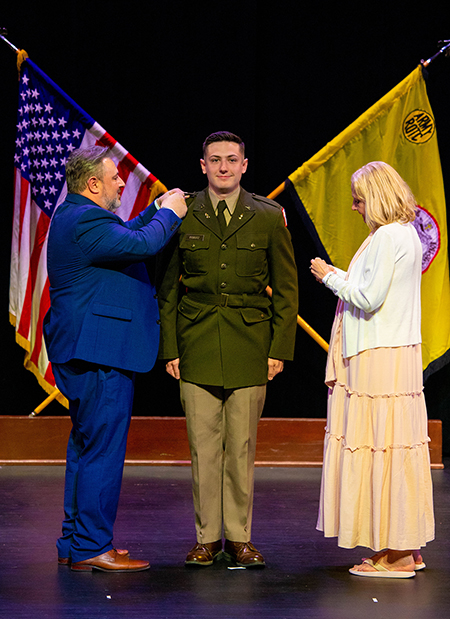 William Piskutz pins the second lieutenant bars on his son, Gavin, with his mother, Cheryl, by his side.