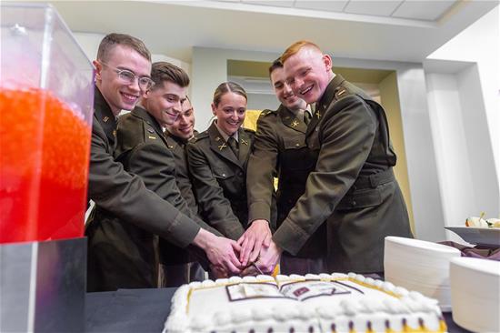 Nely commissioned second lieutenants join forces to slice a cake after the ceremony.