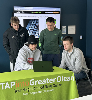 TAPinto Greater Olean staff members confer about a story. Seated are Riley Pendleton (left) and Nathan Laird. Behind them are Christian Figueroa (left) and Aaron Hardy.